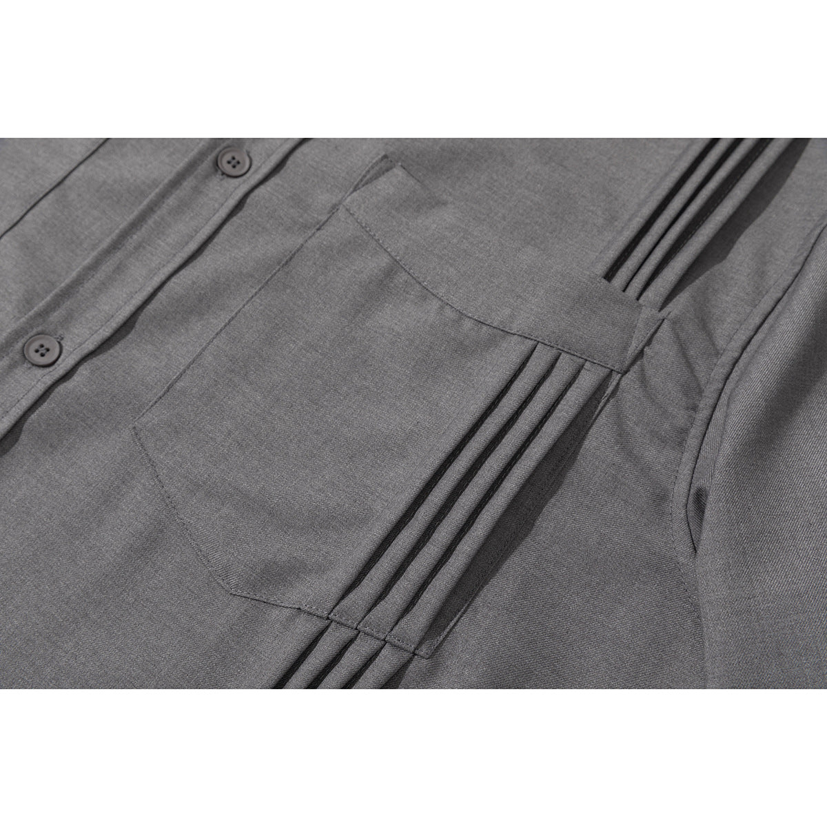 Close-up of a gray shirt's chest pocket, button placket, and parallel stitched pleats.
