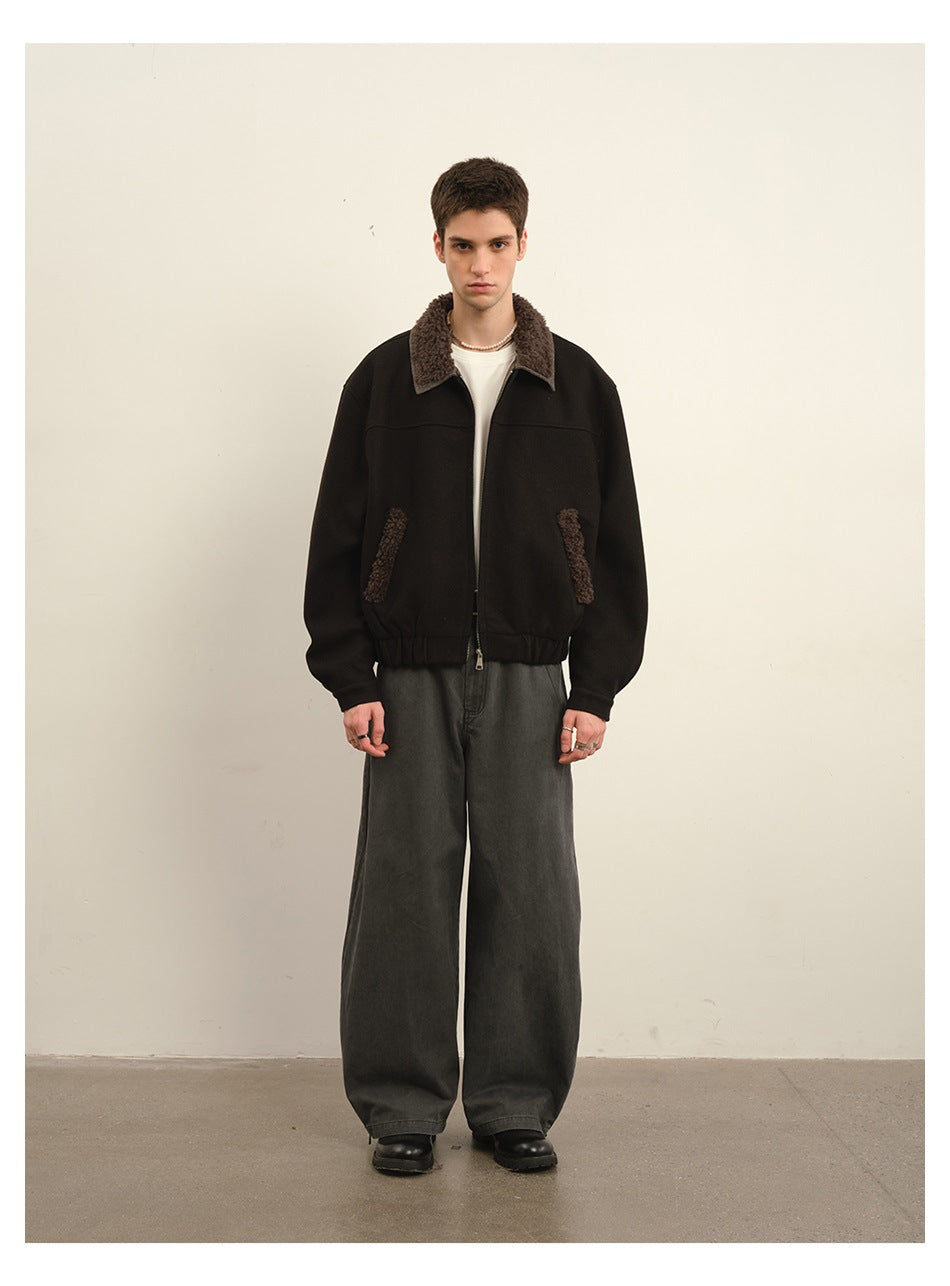 Model wearing dark cropped zip jacket with fleece-like collar over a white tee and wide gray pants, front view
