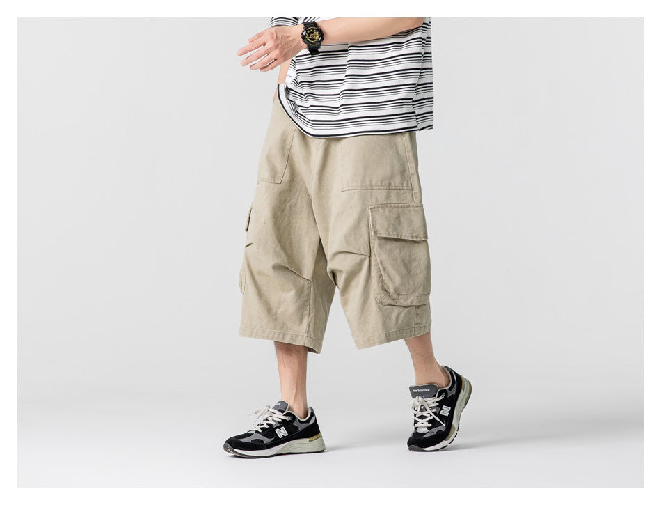 Model wearing loose beige cargo shorts with large side pockets, a striped shirt, and black sneakers.