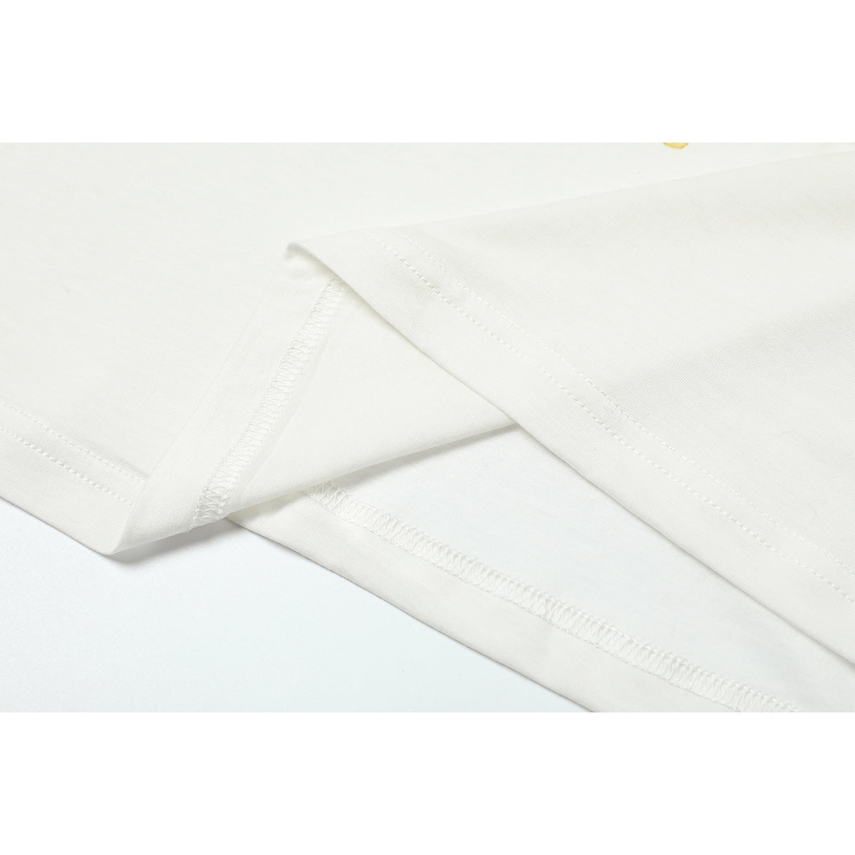 Close-up of white T-shirt fabric showing folded edges and stitched seams.