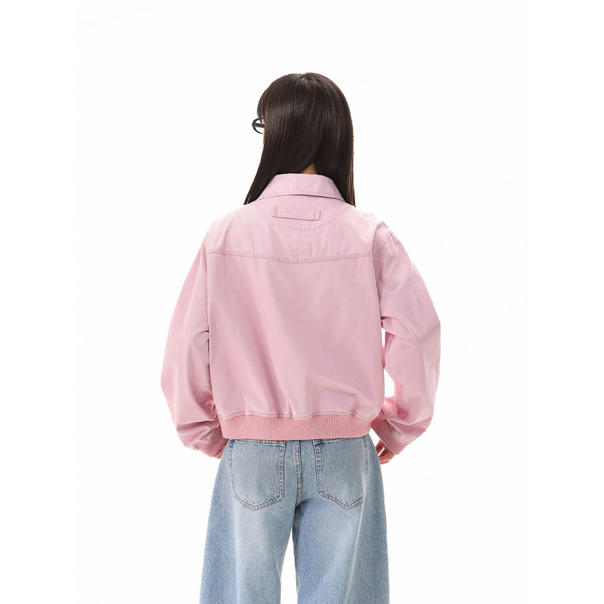 Rear view of a model wearing a light pink jacket with a ribbed hem and cuffs.