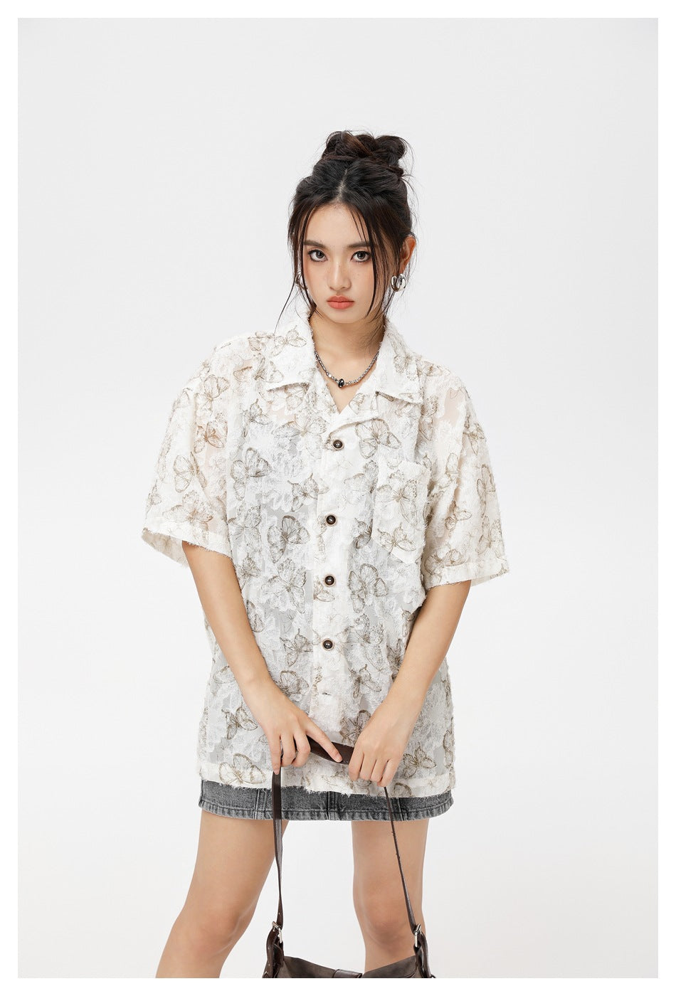 Model wearing an ivory short-sleeve button-up shirt with taupe butterfly and floral patterns.