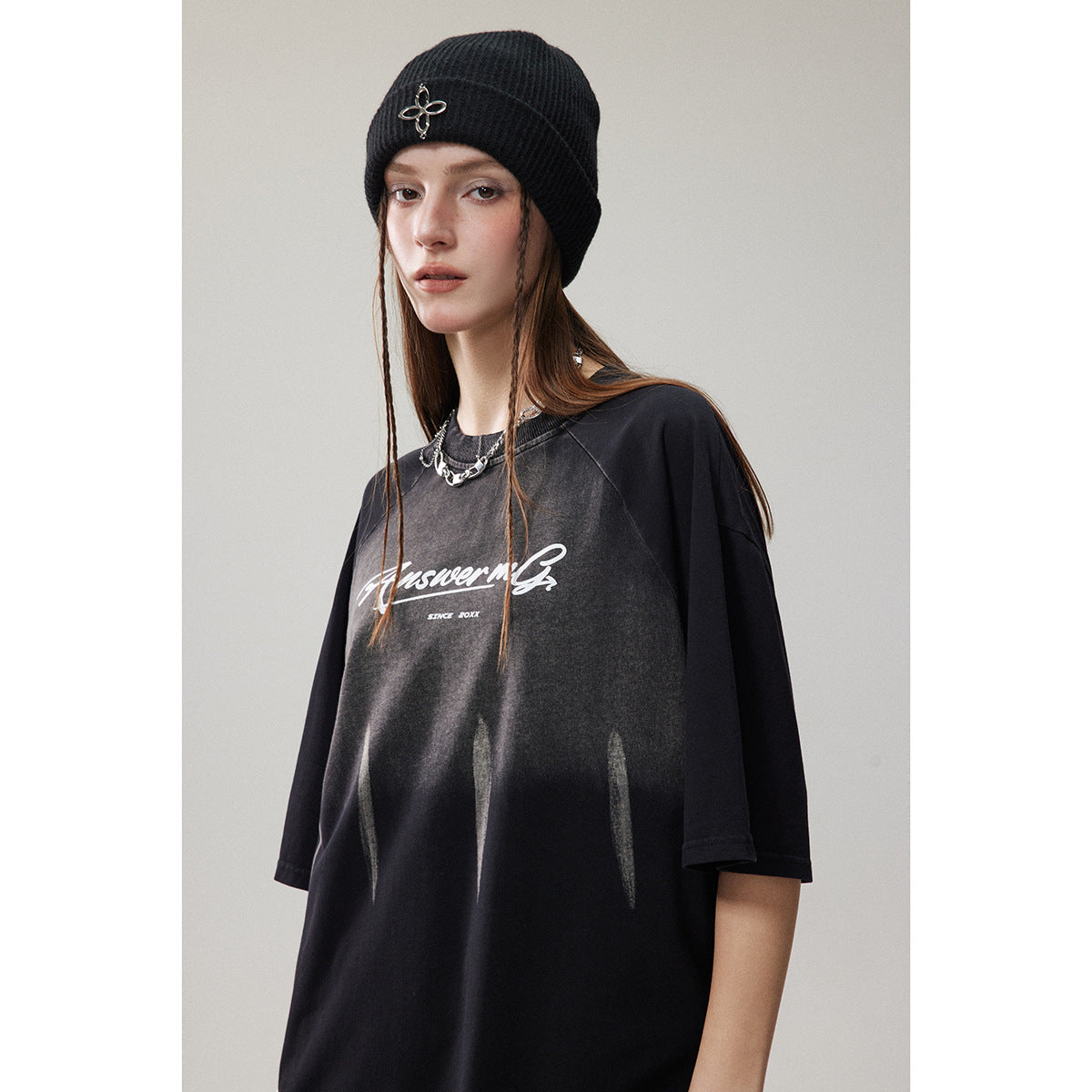 Model wearing an oversized black T-shirt with white script and faded vertical streaks.