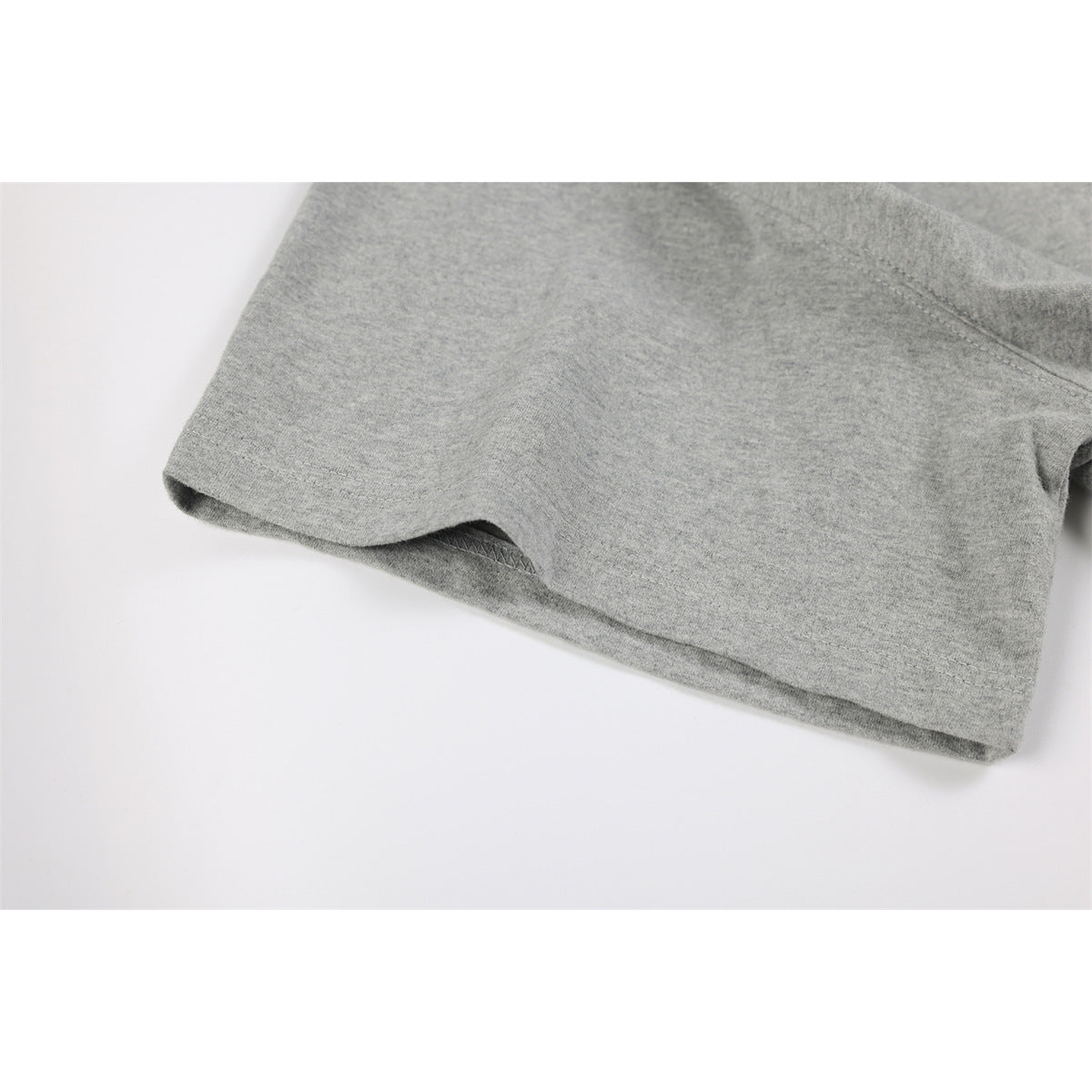 Close-up of a heather gray shirt's short sleeve and stitched hem.