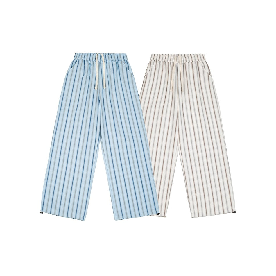 Front view of wide-leg drawstring pants in light blue and cream, both with vertical stripes and elastic waists.