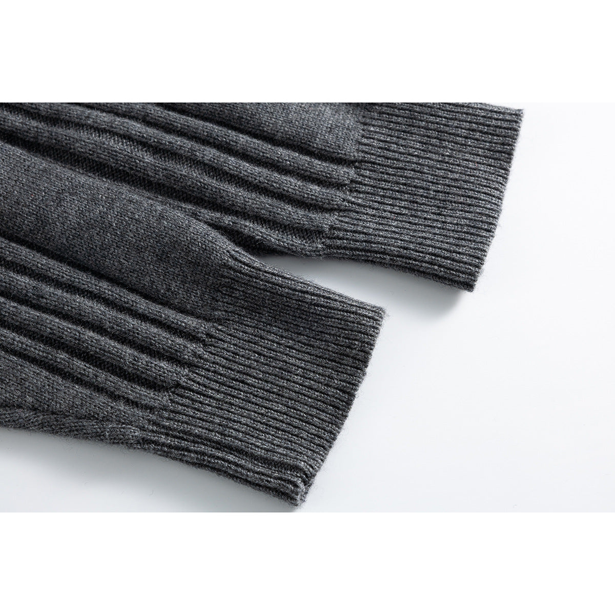 Close-up of charcoal knit sweater sleeves with wide ribbed cuffs and textured stitching.