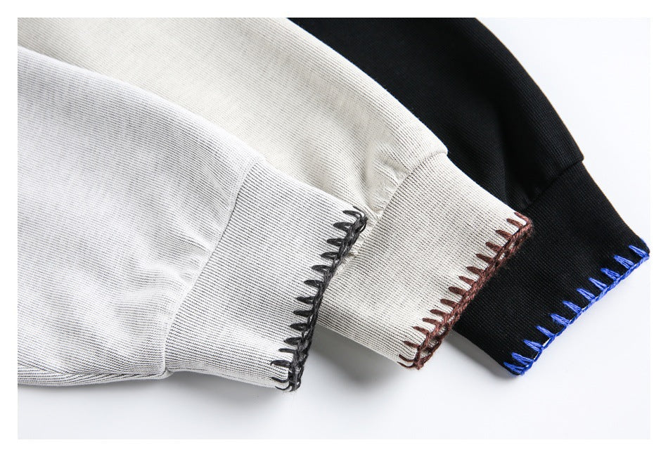 Close-up of gray, ivory, and black sweatshirt cuffs with contrasting blanket stitching.