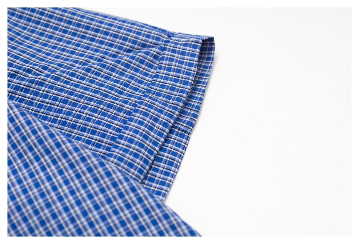 Close-up of blue plaid garment fabric with a folded, stitched edge.