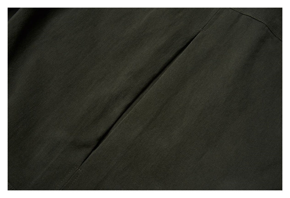 Close-up of a dark olive garment panel with a long diagonal seam and a curved stitched edge.