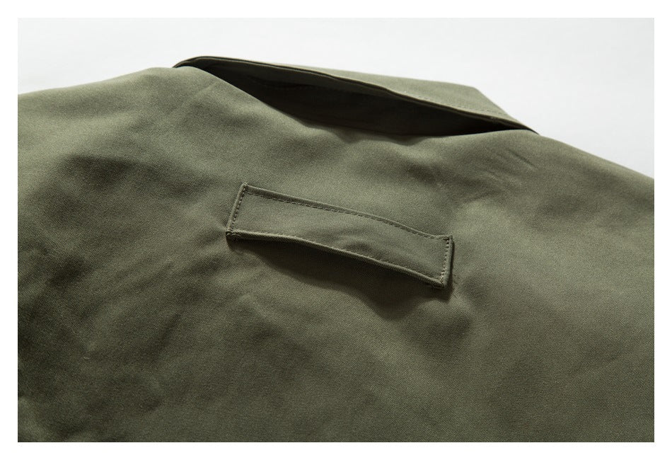 Close-up of an olive jacket showing a stitched rectangular tab beneath the collar.