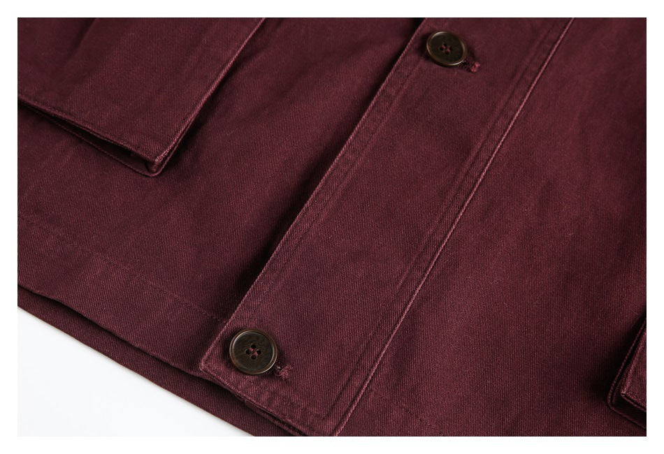 Close-up of burgundy jacket fabric, a pocket edge, and two dark buttons.
