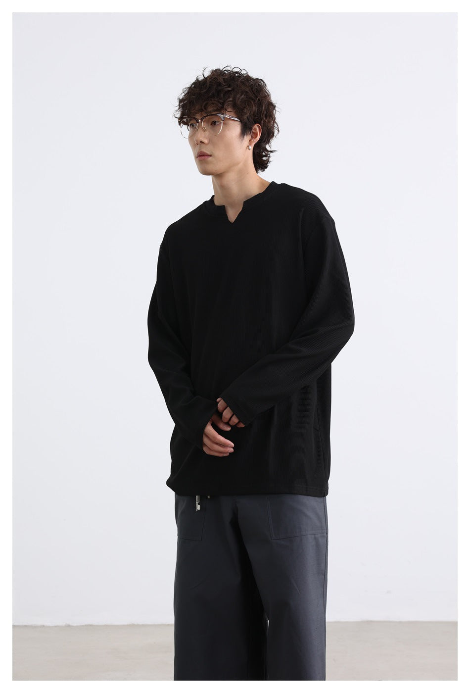 Model wearing a black long-sleeve shirt with a notched neckline, shown from head to upper legs.