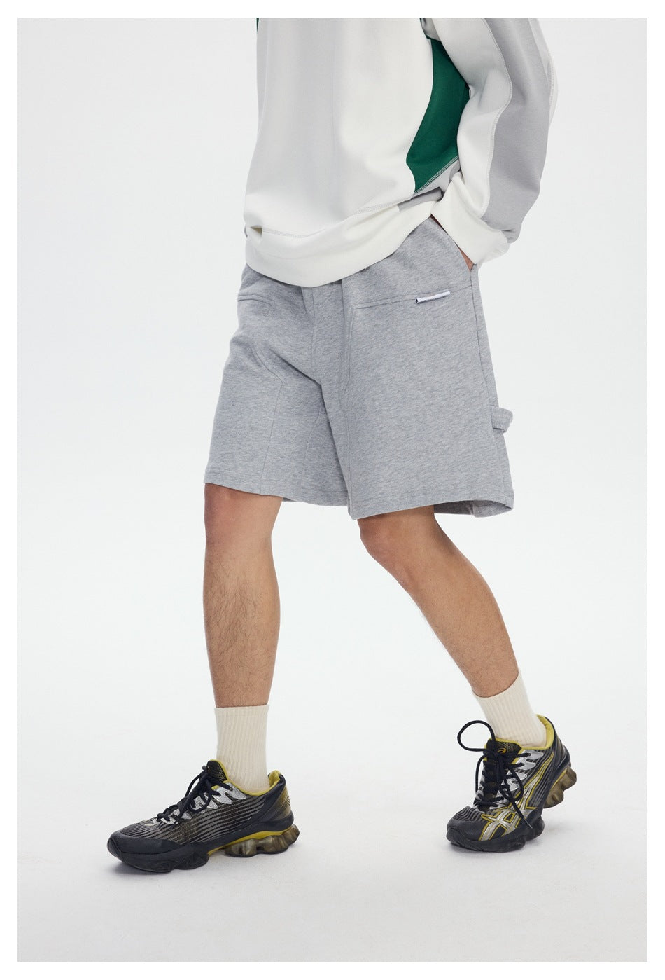Cropped model wearing light gray knee-length shorts with a small pocket and side utility loop.