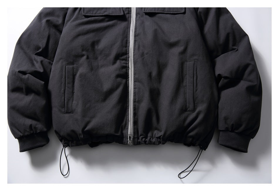 Cropped front view of a black zip-up jacket with flap chest pockets, vertical hand pockets, ribbed cuffs and adjustable hem