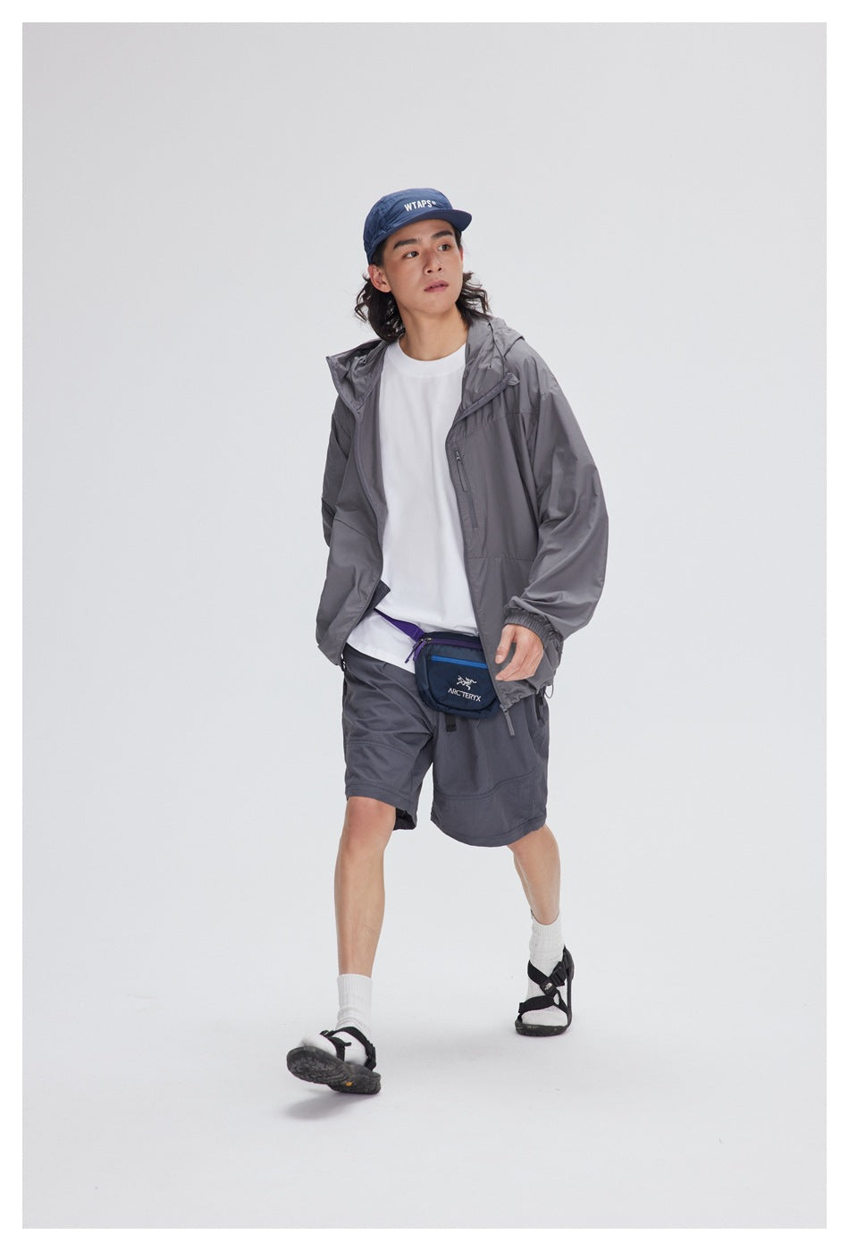 Full-length model wearing an open gray hooded jacket over a white shirt with matching shorts.