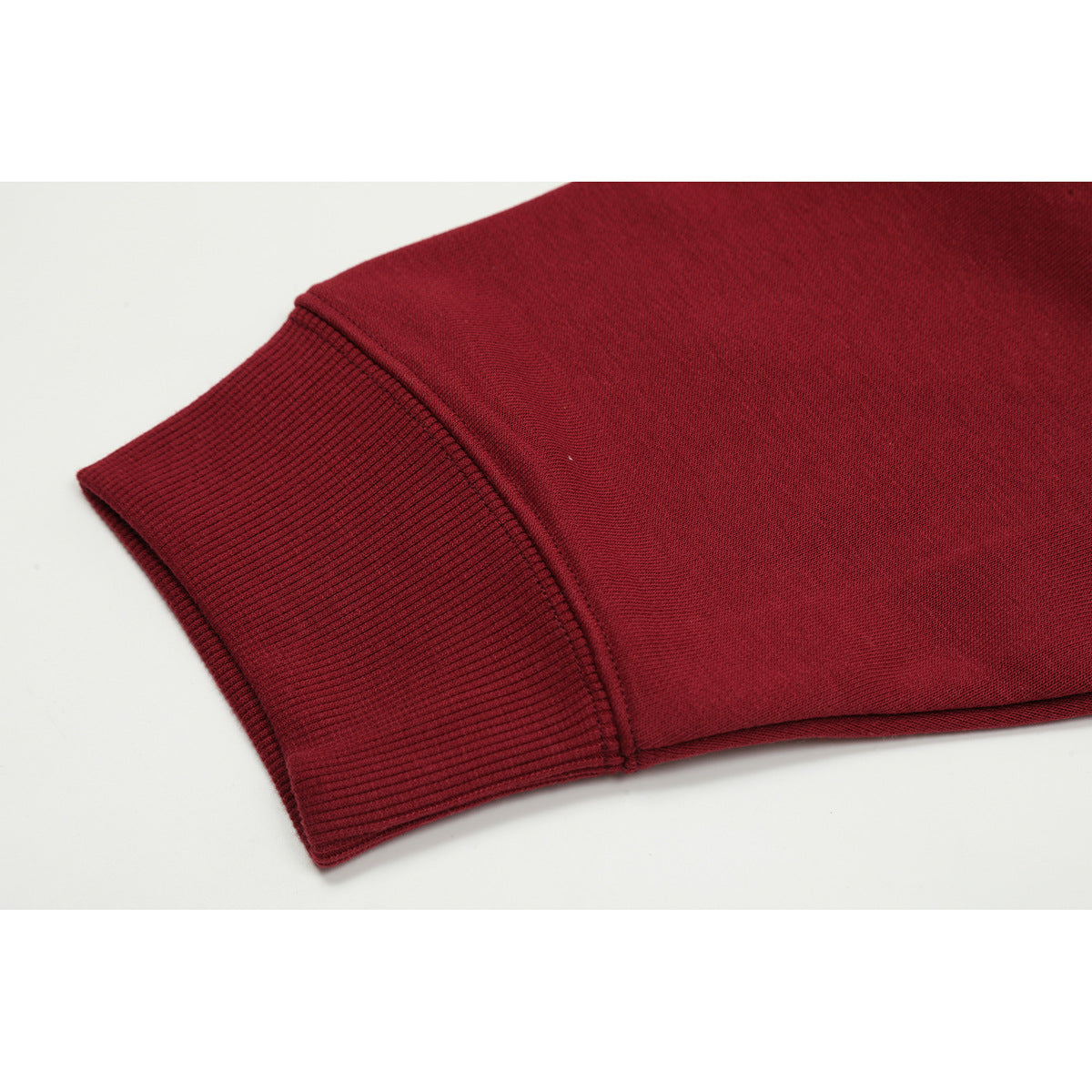 Close-up of a burgundy sweatshirt sleeve ending in a wide ribbed cuff.