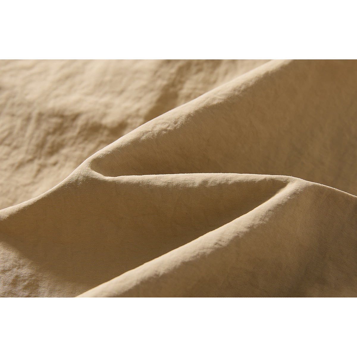 Macro view of the beige shorts fabric, showing its fine surface texture and folds.