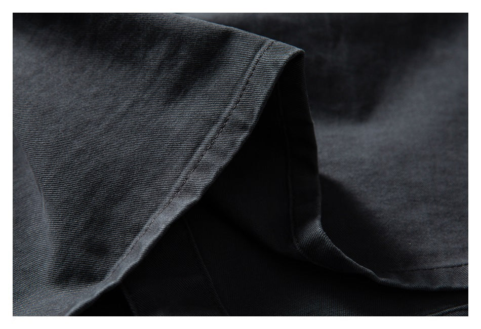 Close-up of dark charcoal fabric with a finished stitched edge and folded layers.