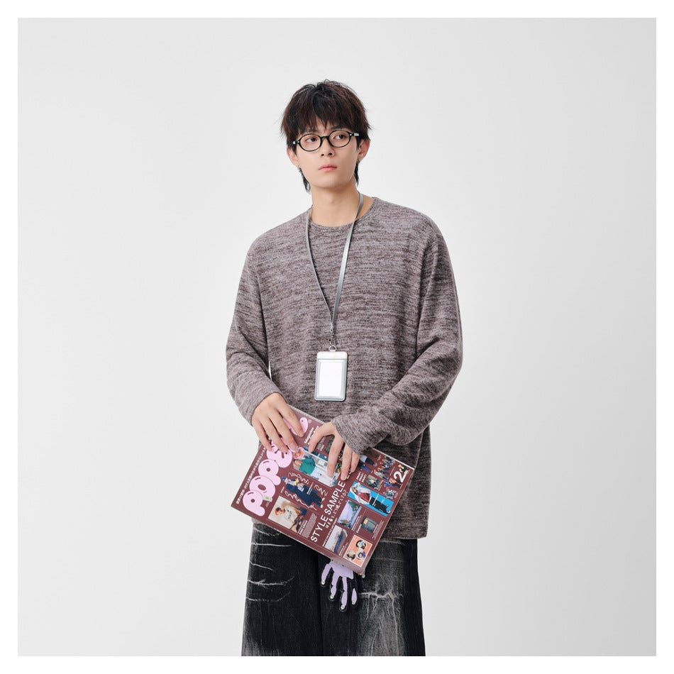 Front view of a model wearing a loose, mottled taupe-gray long-sleeve crewneck sweater.