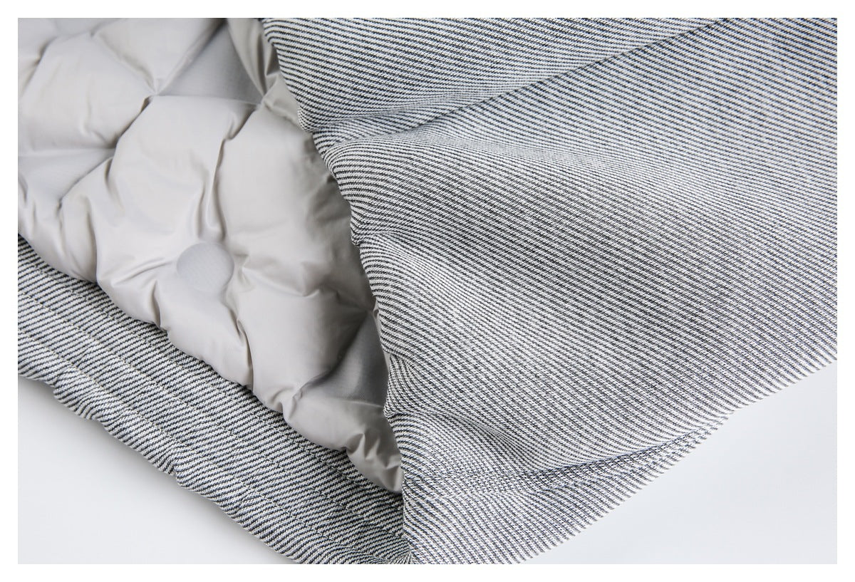 Close-up of a black-and-white finely striped garment opened to show pale gray inner padding and stitched edges.