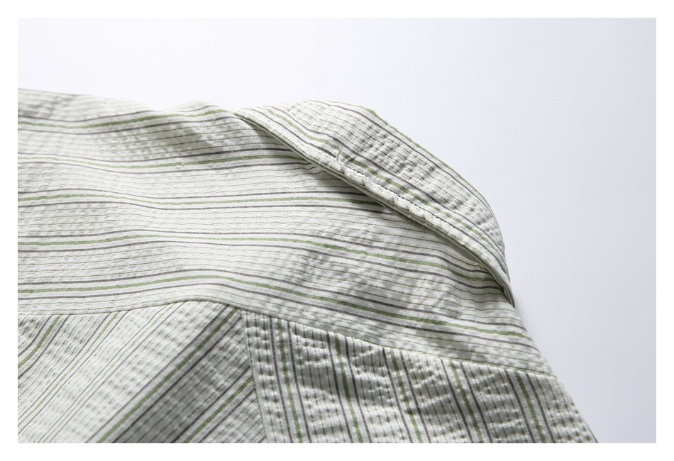 Close-up of the collar and shoulder seam on a white shirt with narrow green and gray stripes.
