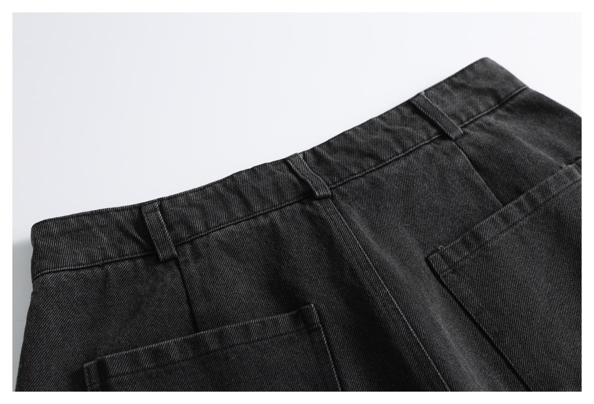 Close-up of black denim trousers showing the waistband, belt loops, and pocket tops.