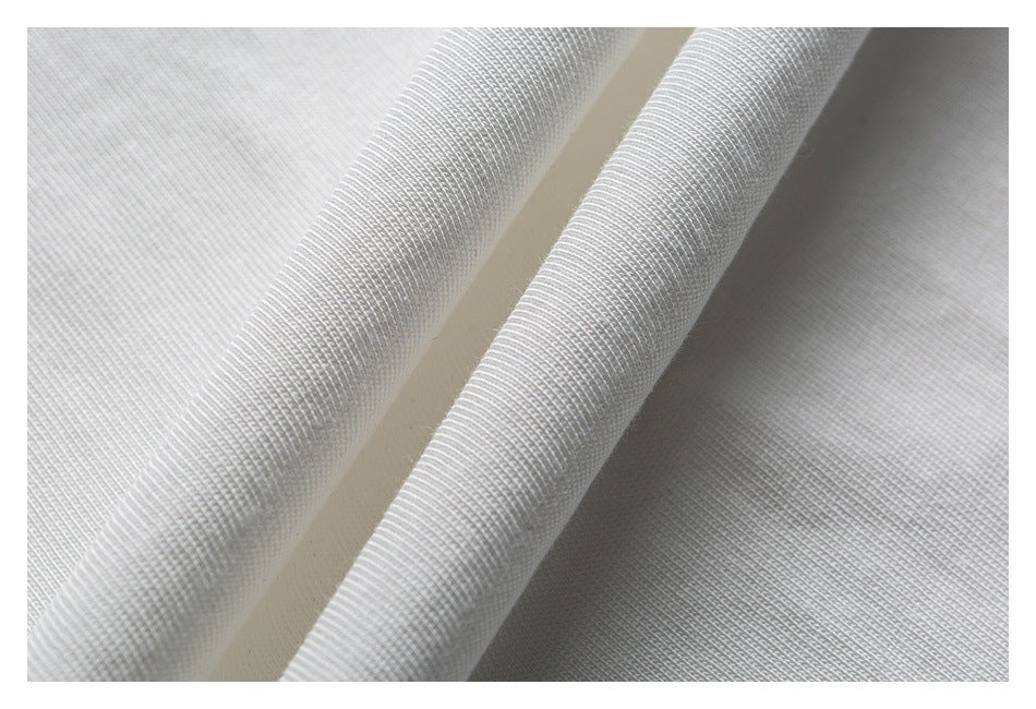 Close-up of white knit fabric folded to show its ribbed texture and layers.