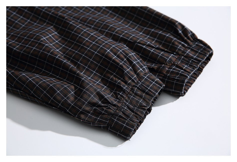 Close-up of gathered elastic cuffs on dark plaid garment legs.