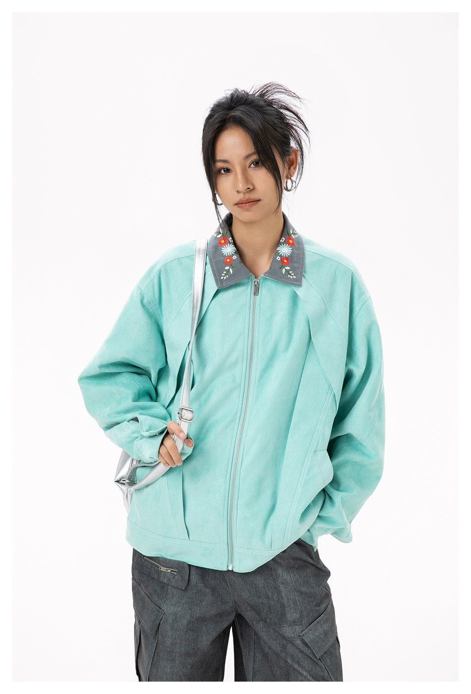 Model wearing a mint zip-front jacket with a gray floral-embroidered collar and dark cargo pants.