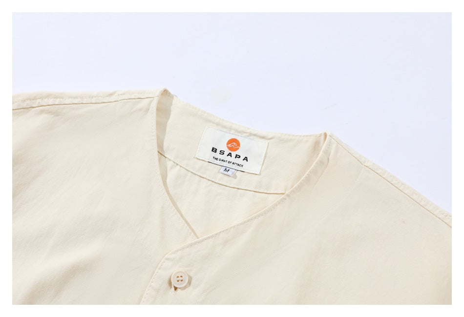 Close-up of the ivory shirt's crossed neckline, button, and sewn-in brand and size labels.