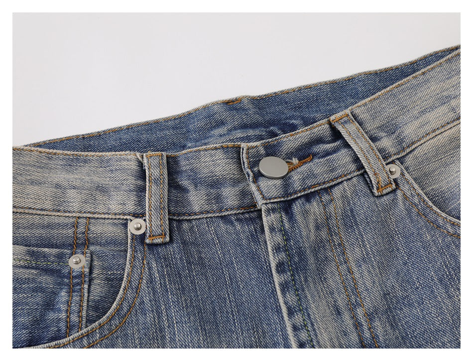 Close-up of the faded blue jeans' front waistband, metal button, belt loops, and pocket stitching.