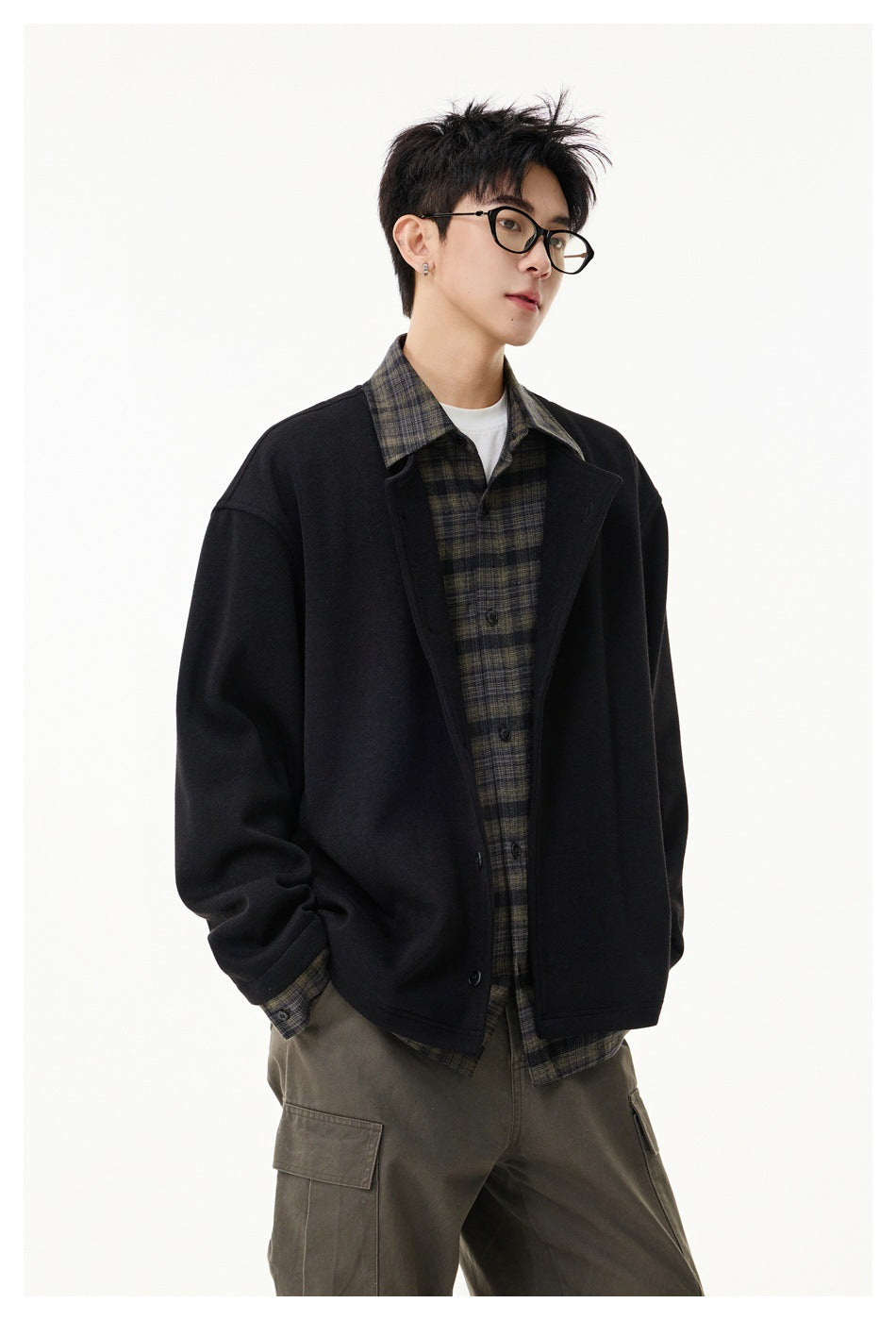 Model wearing a black button-front jacket over a dark plaid shirt and olive cargo pants, shown at an angle.