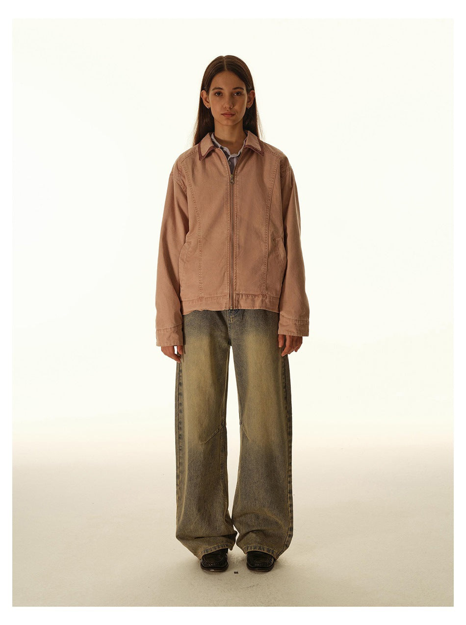 Front view of a woman wearing a dusty rose zip-front jacket with a pointed collar and angled pockets, plus wide-leg jeans.