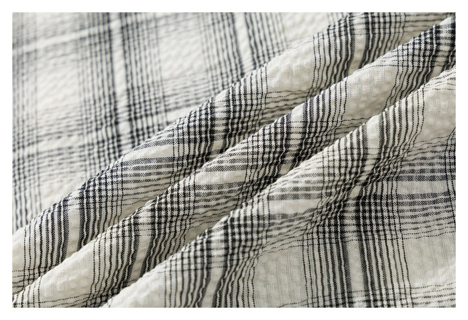 Close-up of the cream and black plaid shirt fabric draped into soft folds.