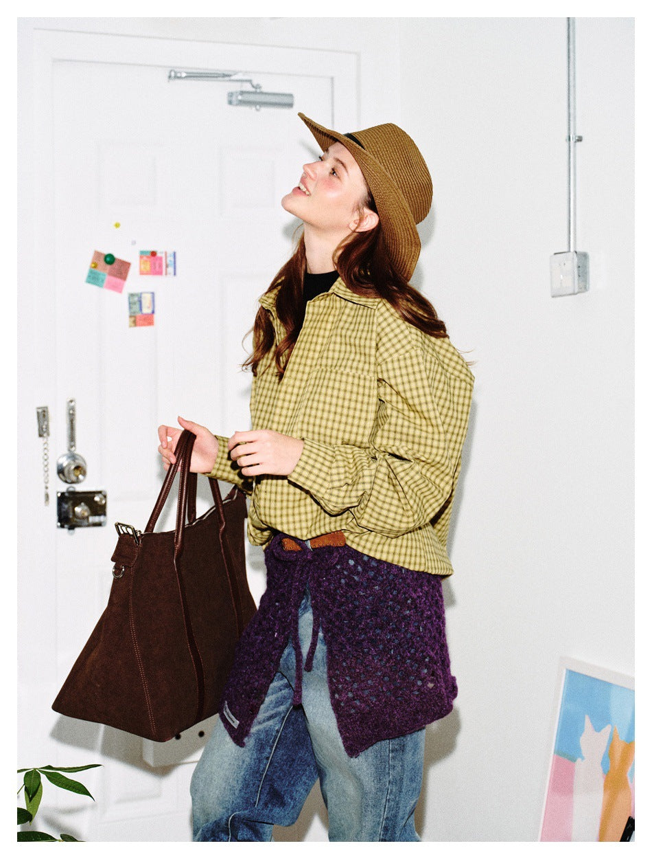 Side view of a model in a yellow checked shirt, purple knit wrap, and blue jeans.