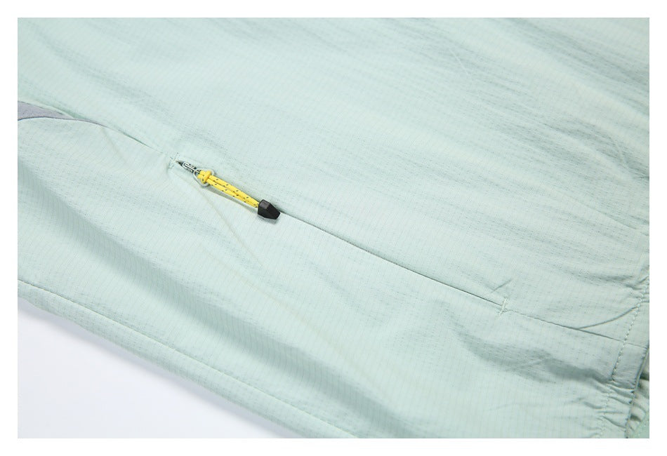 Close-up of a slanted zip pocket on pale mint fabric, with a yellow-and-black zipper pull.