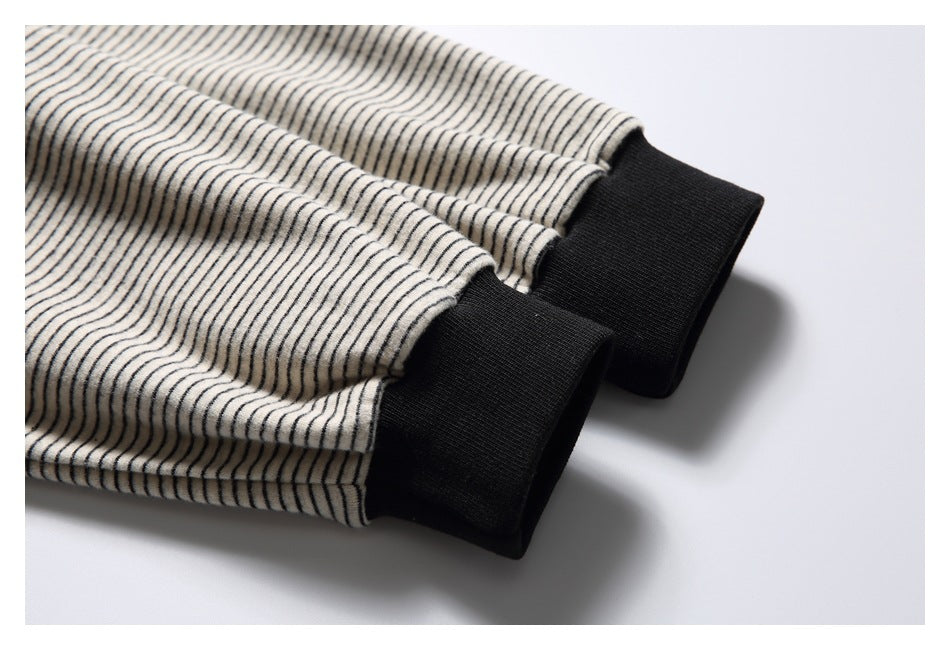 Close-up of two black ribbed cuffs on cream-and-black striped sleeves.