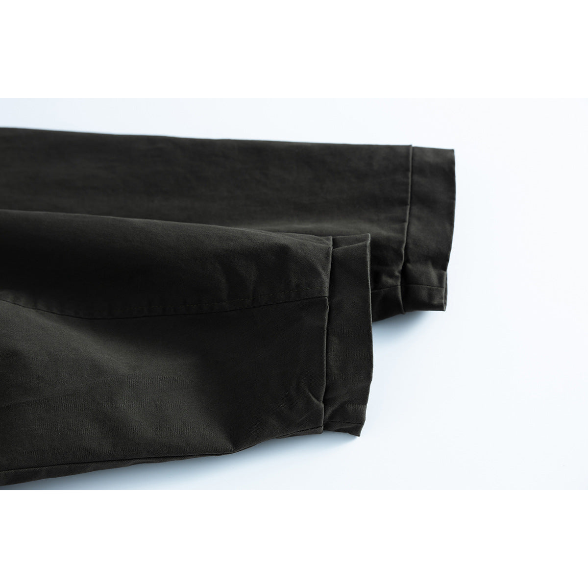 Close-up of the dark jacket’s long sleeve cuffs and stitched hems.