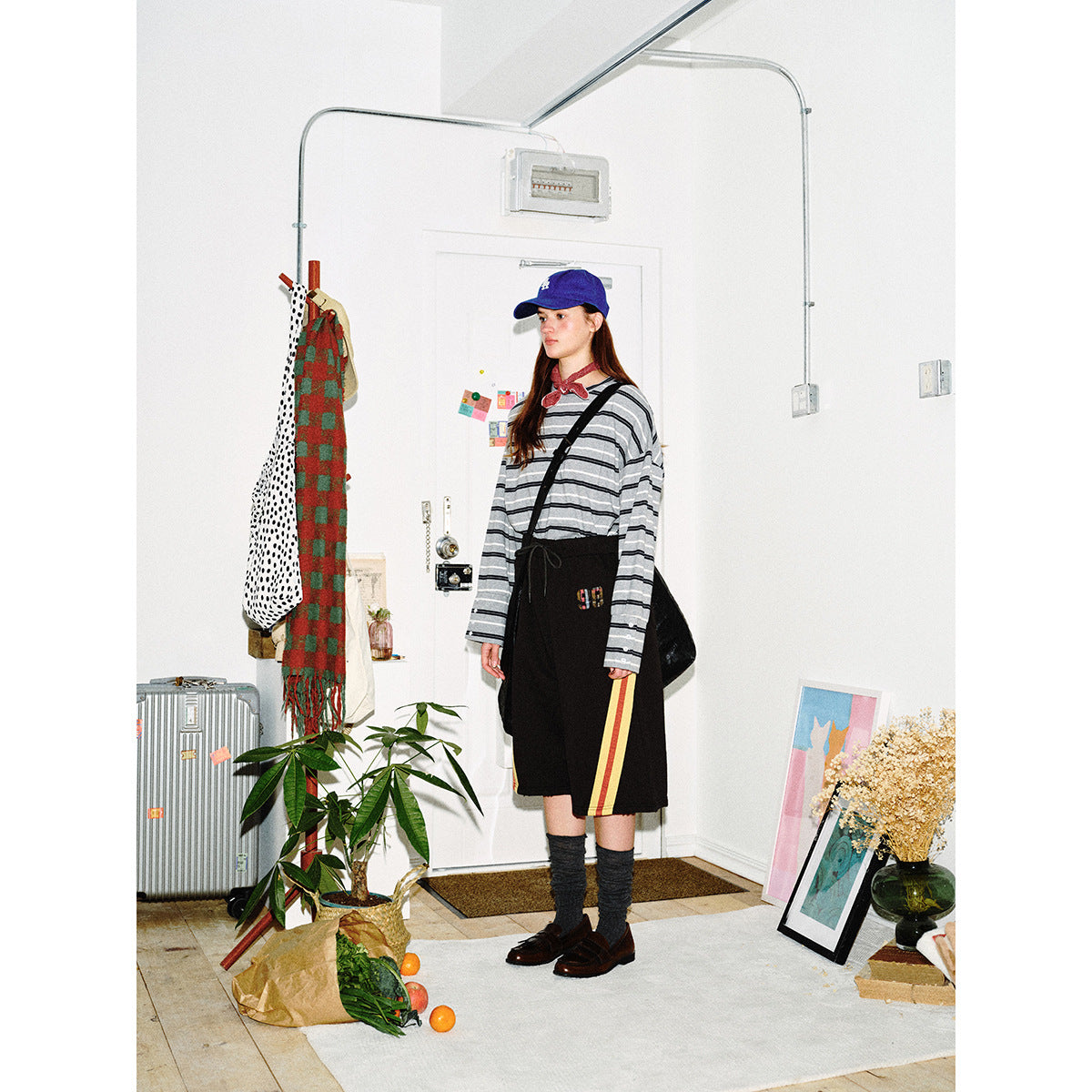 Model in a gray and black striped long-sleeve shirt and black shorts with red and yellow side stripes, shown at a slight
