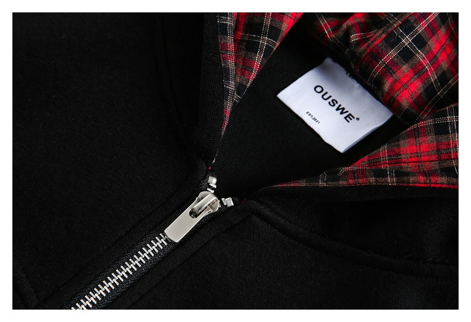 Close-up of the black hoodie’s silver zipper, red plaid hood lining and sewn neck label.