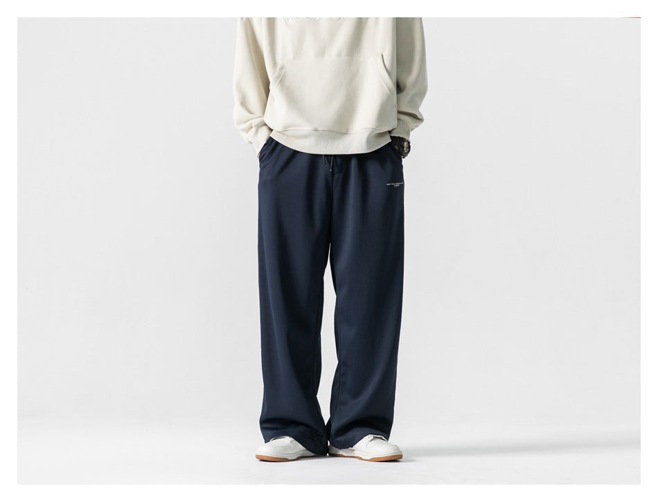 Model wearing loose navy wide-leg pants with a cream sweatshirt and white sneakers, front view.