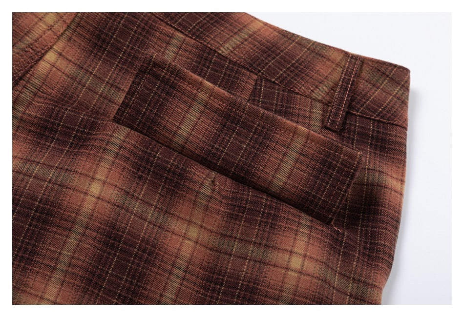 Close-up of brown plaid trousers showing a belt loop and pocket seam.