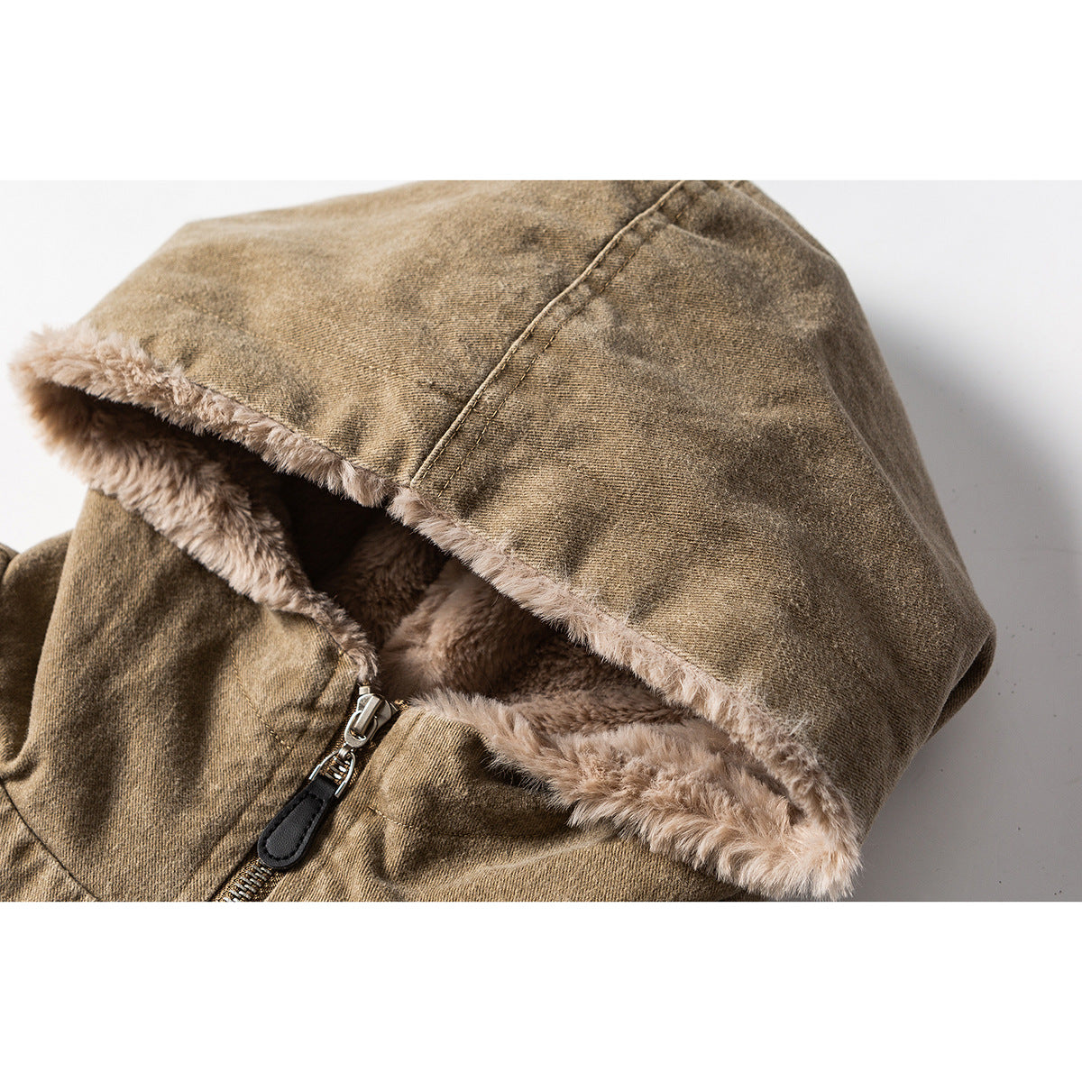 Close-up of an olive-brown jacket hood with plush beige lining and a metal zipper.