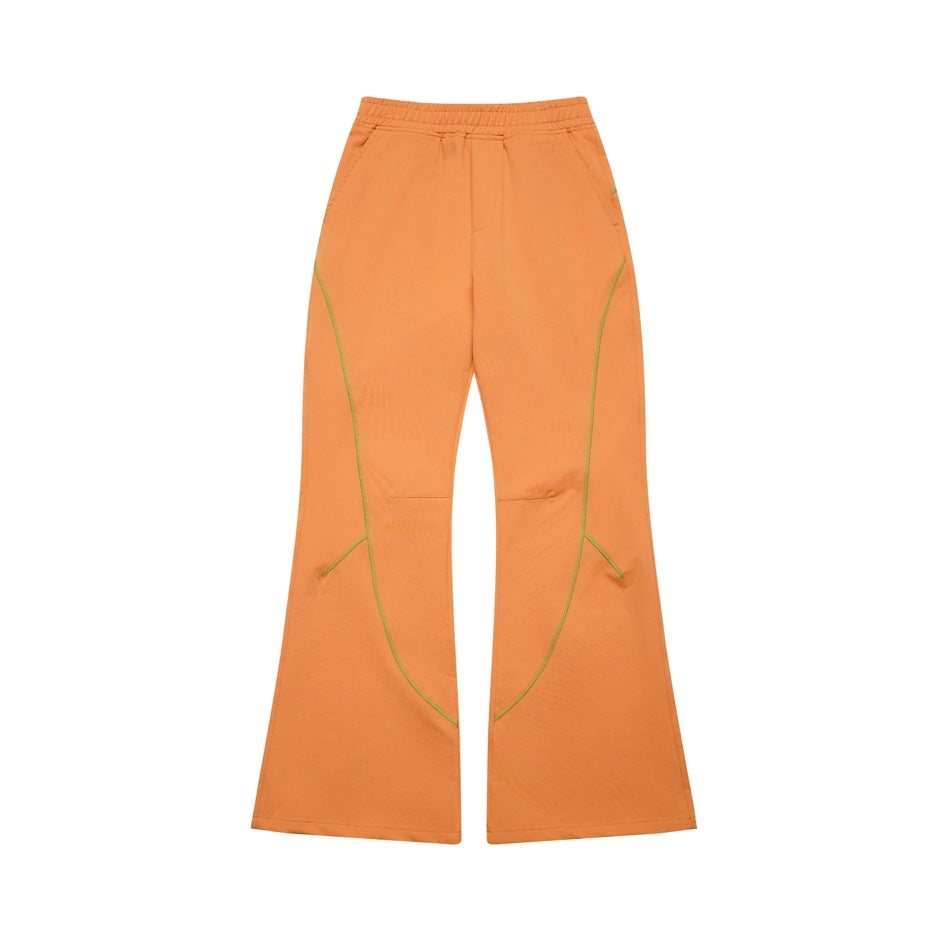 Orange flared pants with elastic waistband and green curved contrast topstitching, flat front view