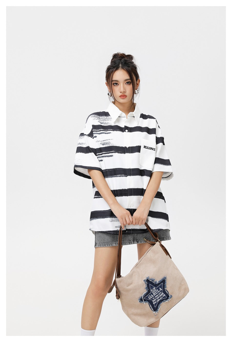 Front view of a model in an oversized white shirt with black brushstroke stripes and chest pocket, paired with a gray denim