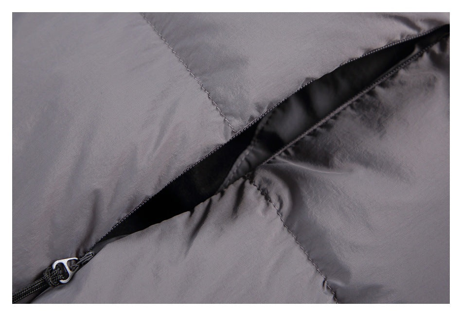 Close-up of a gray puffer jacket's zippered pocket opening and quilted fabric.