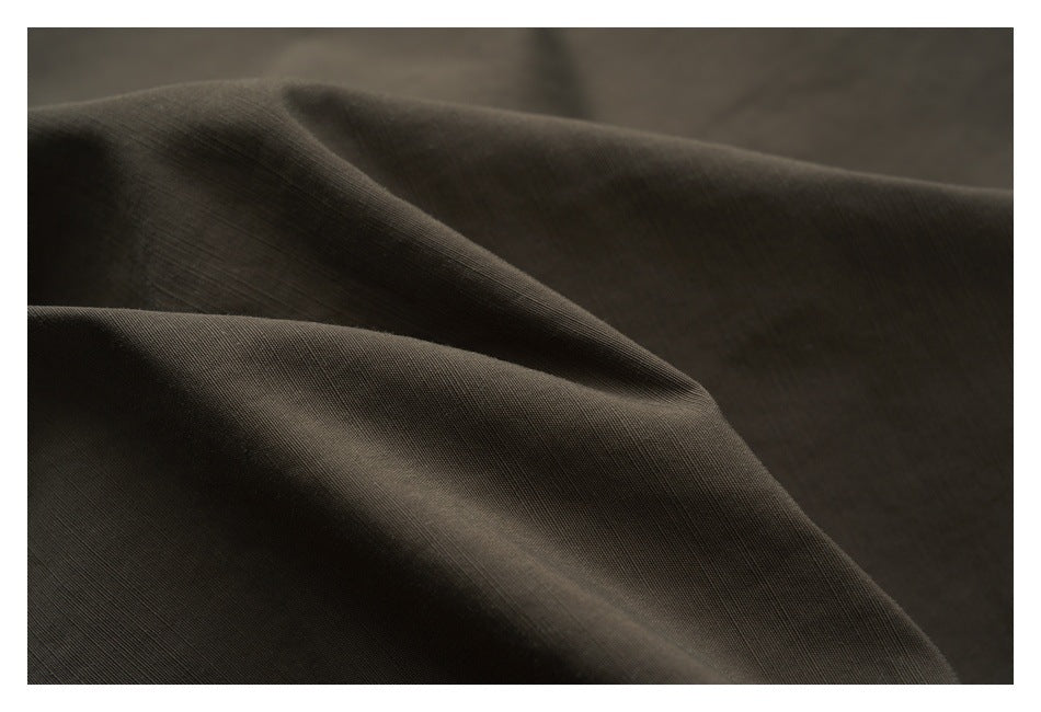 Close-up of dark brown fabric draped in soft folds, showing its fine surface texture.