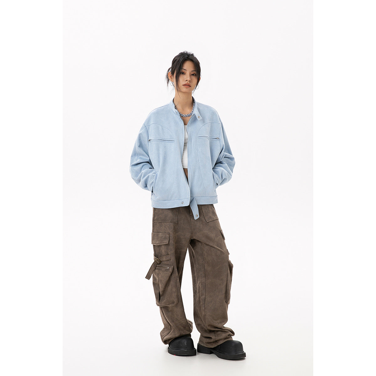 Model wearing a light blue zip-front jacket with chest zips and brown cargo pants, shown from the front.