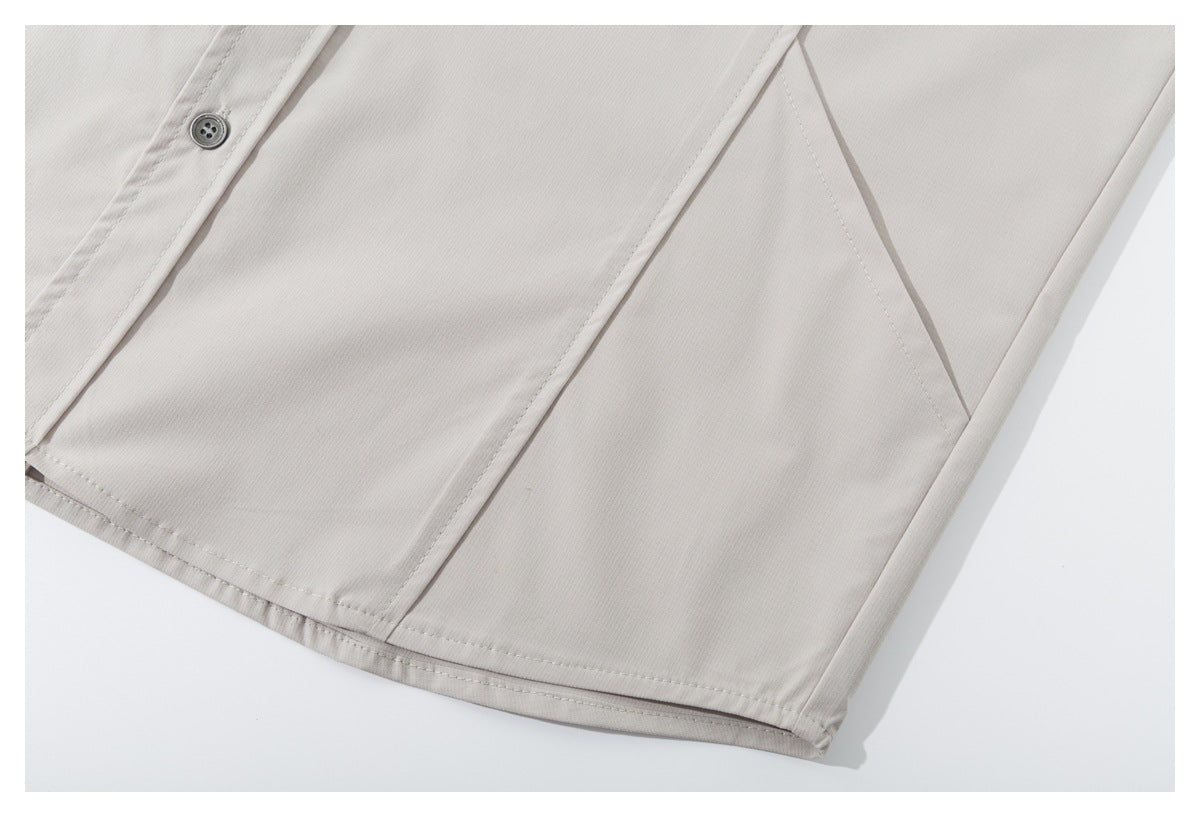 Close-up of the light beige shirt's lower front, button placket, side seam, and curved hem stitching.