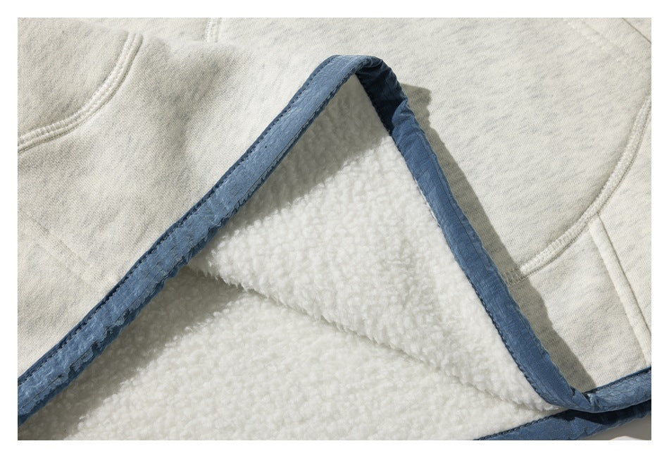 Folded edge of a light heather-gray garment reveals a plush white interior and blue binding.